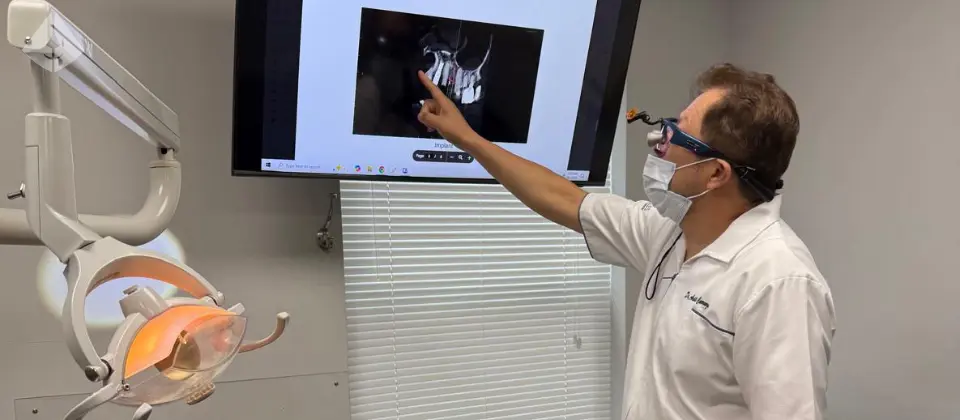 Dr. Aristo Carranza discussing a 3D dental scan with an adult patient for a wisdom tooth extraction at Smile Design NJ.